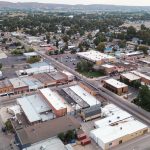 Emmett ID 22 Aerial view of a small town with grid streets, low-rise buildings, houses, and trees, surrounded by distant hills under a hazy sky. In Emmett, ID.